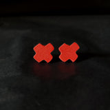 Red X-shaped earrings on a black background