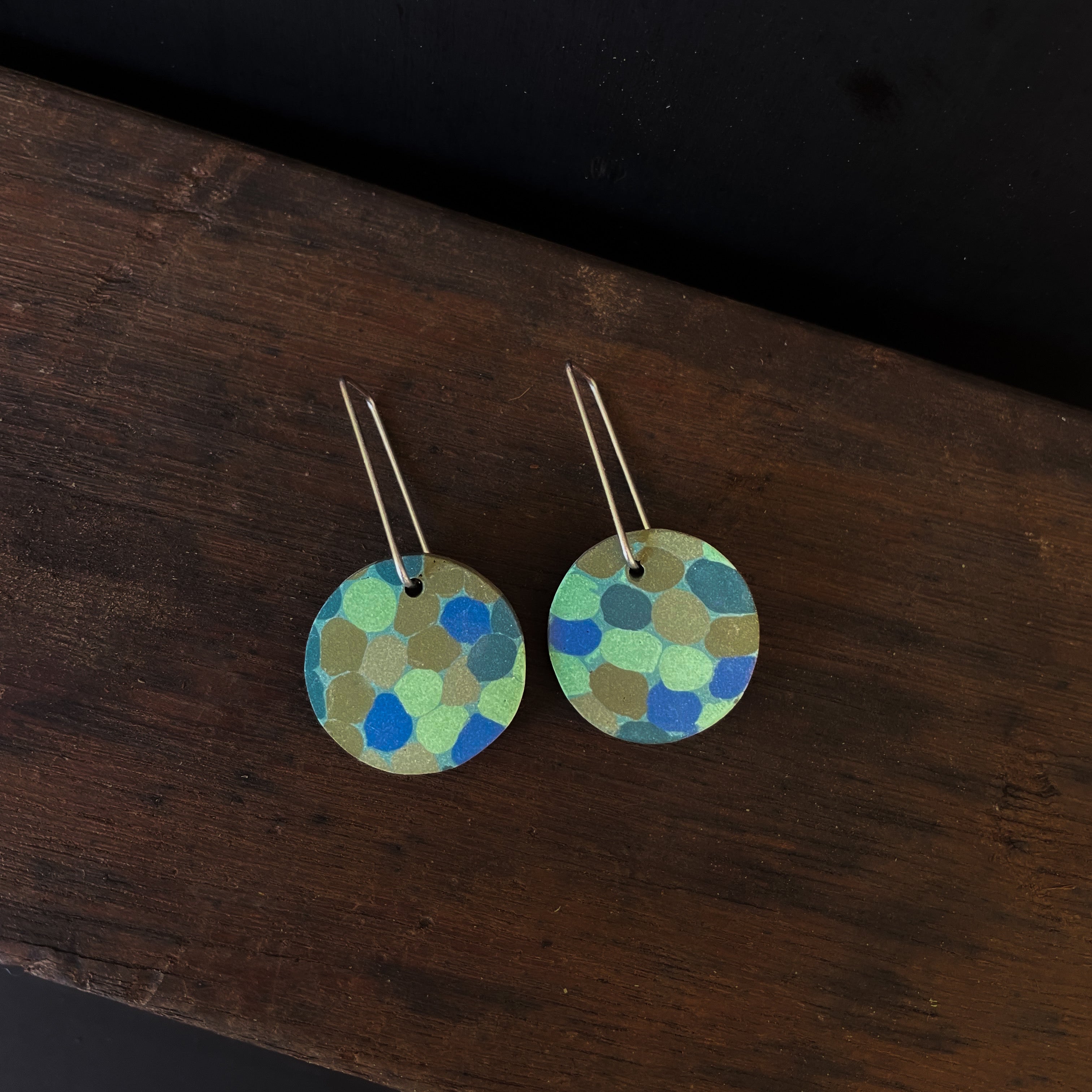 Round earrings with a polka dot pattern on a wooden surface