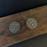 Round earrings with a honeycomb pattern on a wooden surface