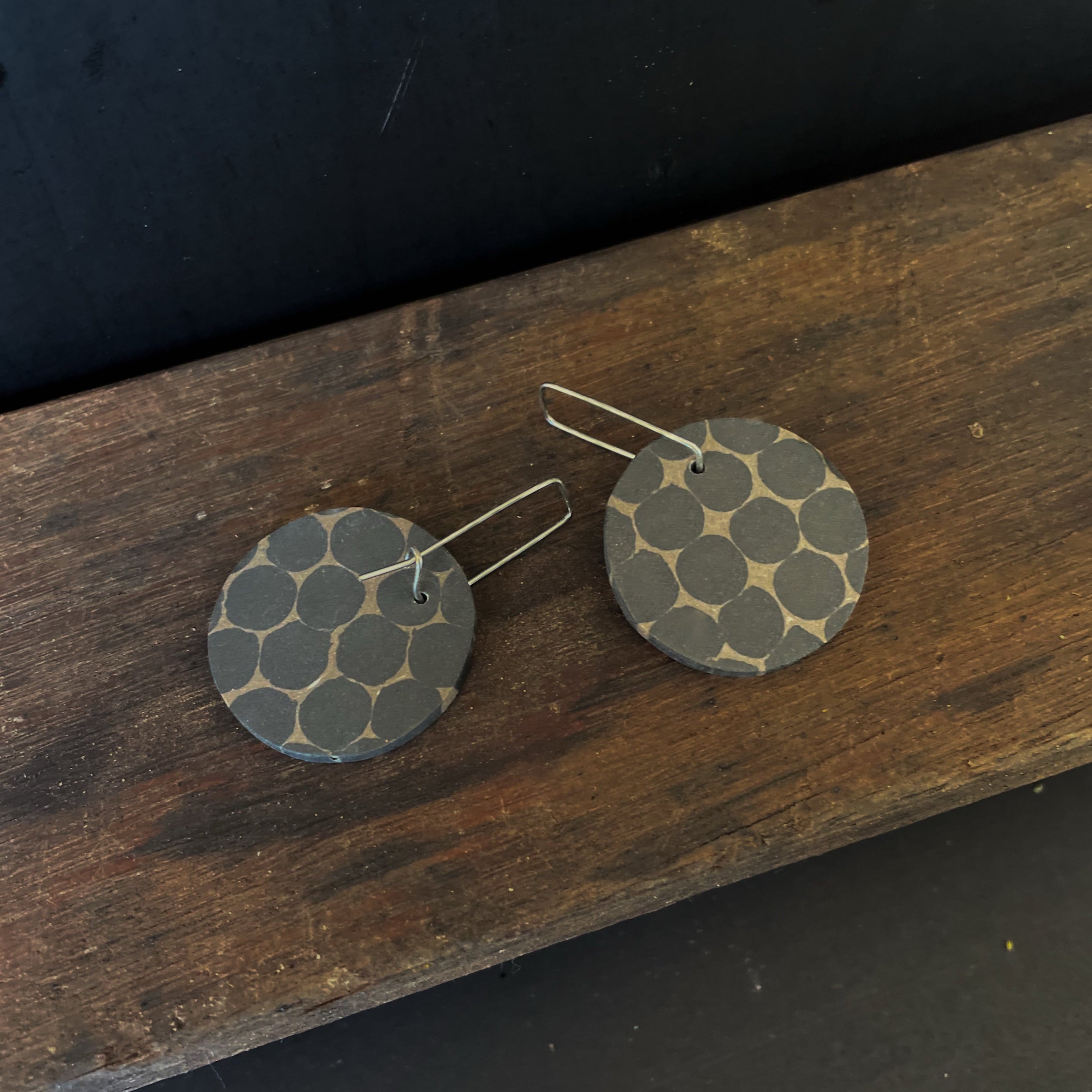 Round earrings with a honeycomb pattern on a wooden surface