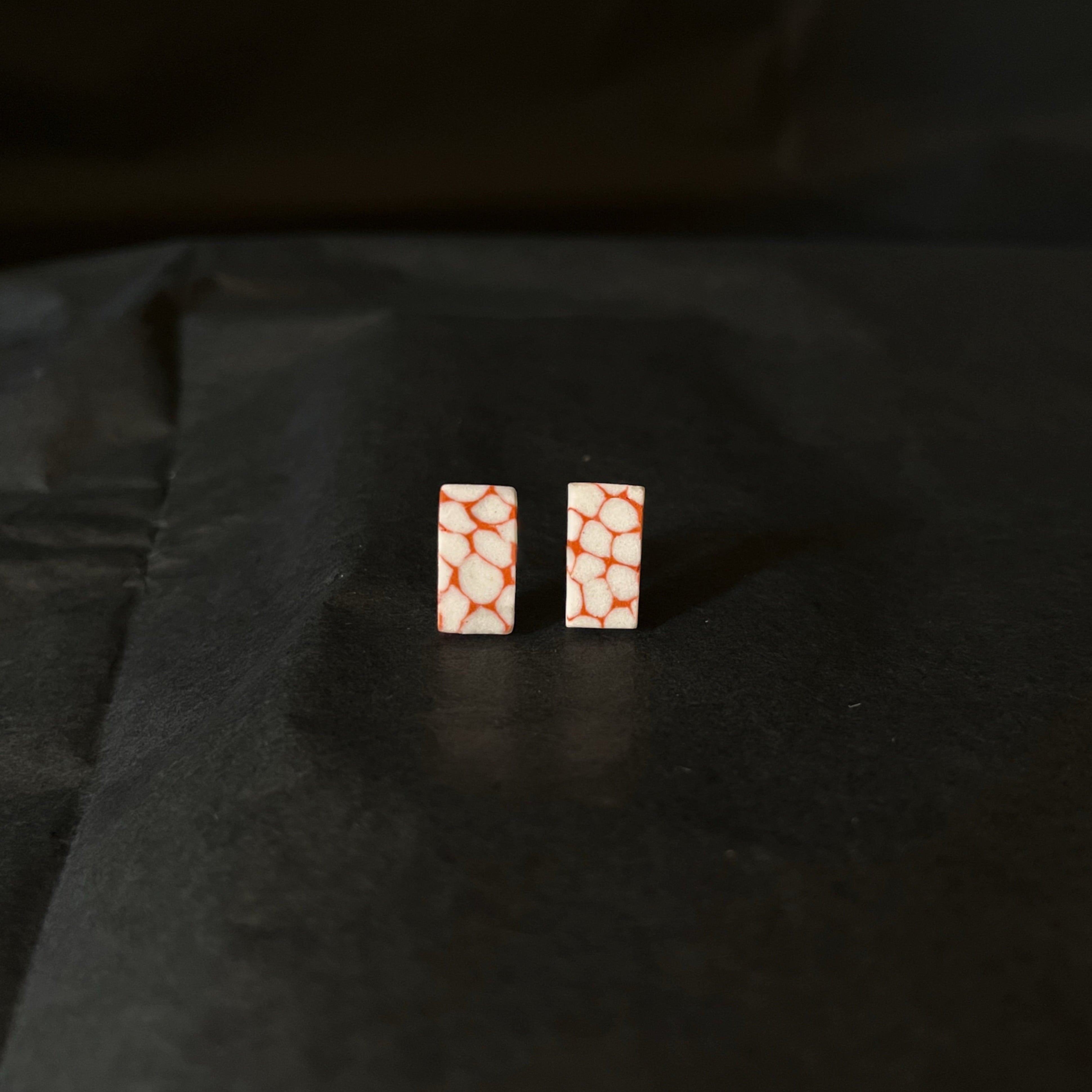 Rectangular earrings with a Terracotta brown and white pattern on a black background